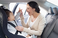 A mother buckles her baby into its car seat